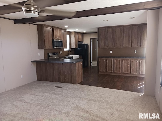 kitchen with appliances with stainless steel finishes, a peninsula, dark countertops, a sink, and recessed lighting