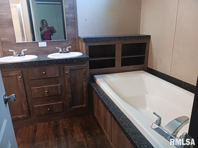 full bath featuring wood finished floors, a bath, and double vanity