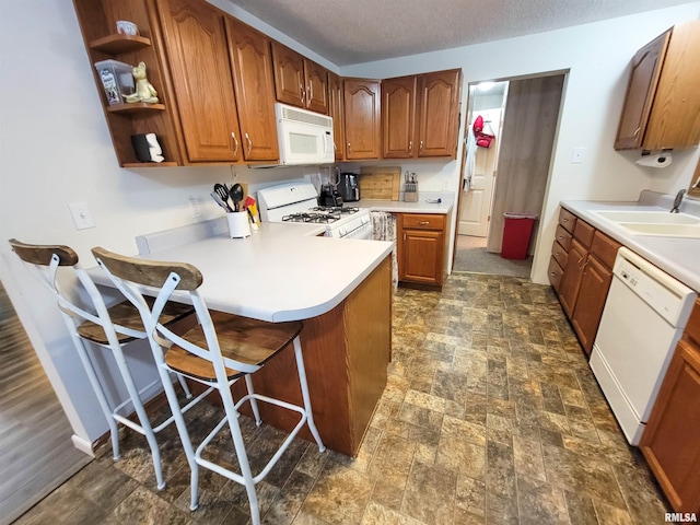 214 W 12th St, Flora, IL 62839 - kitchen featuring white appliances, a sink, brown cabinets, a peninsula, and light countertops