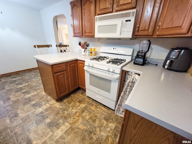 214 W 12th St, Flora, IL 62839 - kitchen with white appliances, arched walkways, a peninsula, brown cabinets, and stone finish flooring
