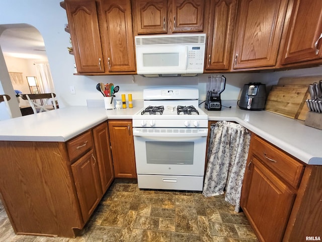 214 W 12th St, Flora, IL 62839 - kitchen with white appliances, arched walkways, brown cabinetry, and a peninsula