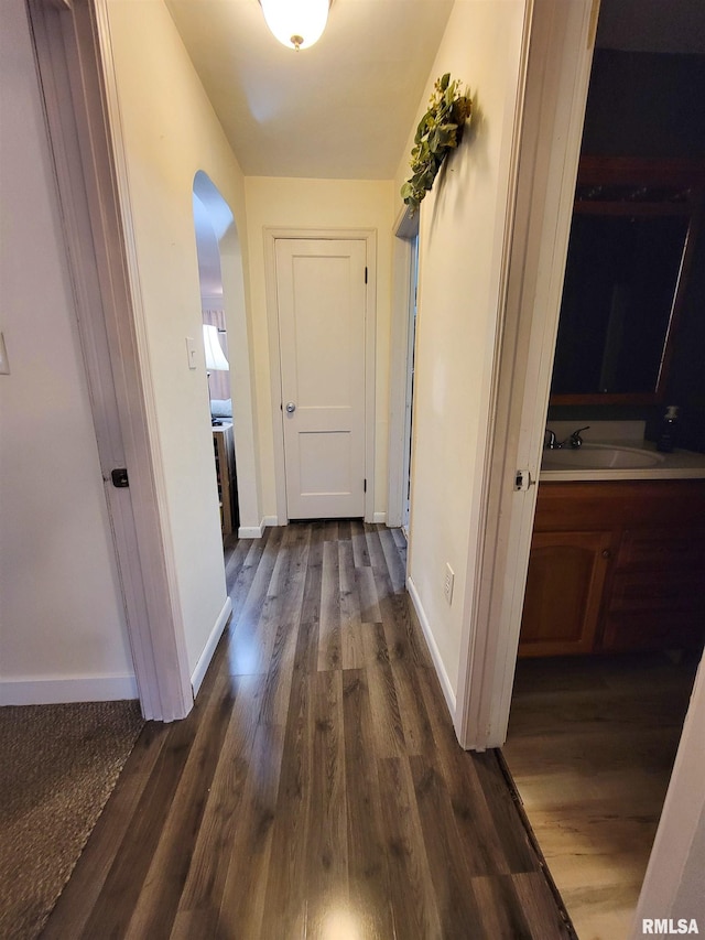 214 W 12th St, Flora, IL 62839 - hall featuring arched walkways, dark wood-type flooring, baseboards, and a sink