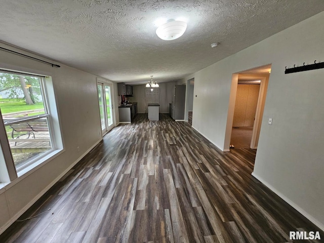 901 W 4th St, Bluford, IL 62814 - unfurnished living room with dark wood-type flooring, a textured ceiling, baseboards, and a chandelier