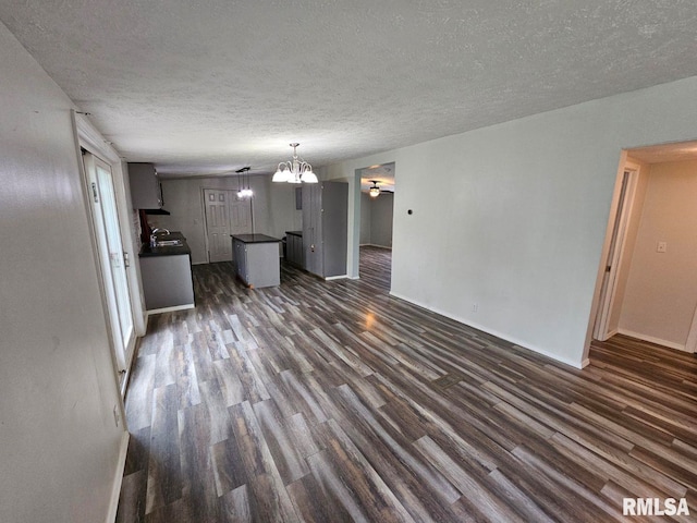 901 W 4th St, Bluford, IL 62814 - unfurnished living room with dark wood-style flooring, a textured ceiling, a chandelier, and baseboards