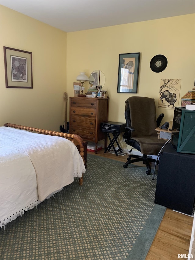 bedroom featuring wood finished floors and a desk