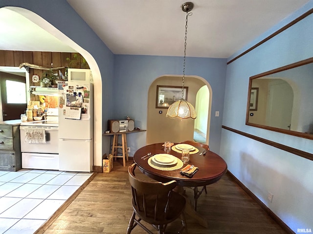 dining area featuring arched walkways and wood finished floors