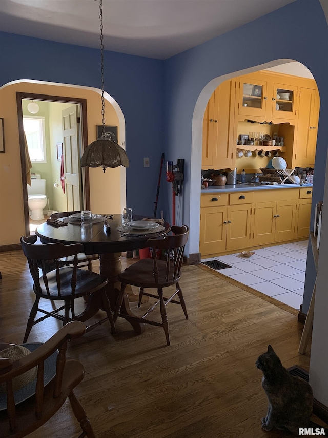 dining area with arched walkways, light wood-type flooring, and baseboards