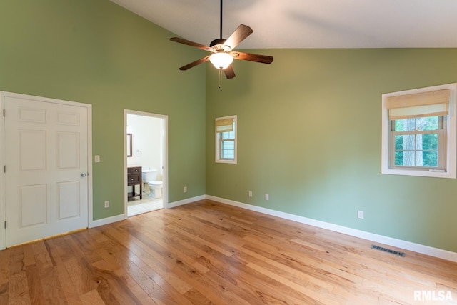 1021 Meadowlark Dr, Carterville, IL 62918 - unfurnished bedroom featuring high vaulted ceiling, light wood-style flooring, multiple windows, ensuite bathroom, and baseboards