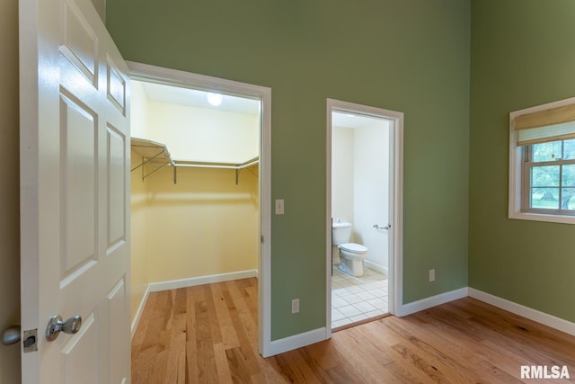 1021 Meadowlark Dr, Carterville, IL 62918 - unfurnished bedroom with light wood-style floors, baseboards, a spacious closet, a closet, and connected bathroom