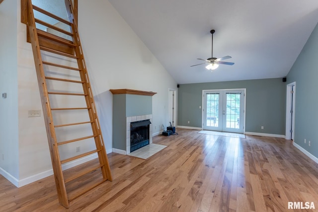 1021 Meadowlark Dr, Carterville, IL 62918 - unfurnished living room featuring french doors, ceiling fan, light wood-type flooring, a tiled fireplace, and baseboards