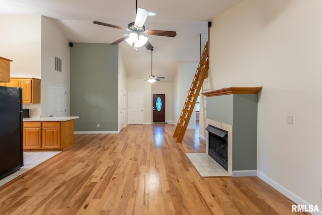 1021 Meadowlark Dr, Carterville, IL 62918 - unfurnished living room featuring high vaulted ceiling, a ceiling fan, light wood-style flooring, baseboards, and a tile fireplace
