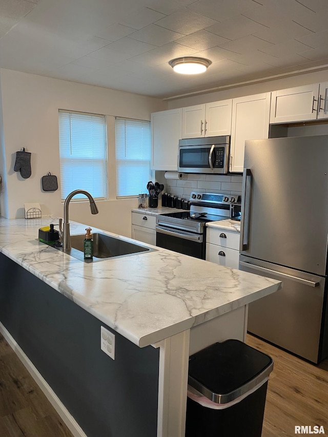 717 E Main St, Benton, IL 62812 - kitchen with stainless steel appliances, a sink, wood finished floors, a peninsula, and white cabinetry