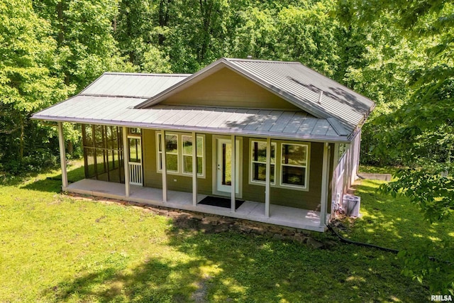 back of property featuring covered porch, a lawn, and metal roof