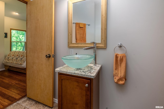 bathroom with ensuite bath, vanity, and baseboards