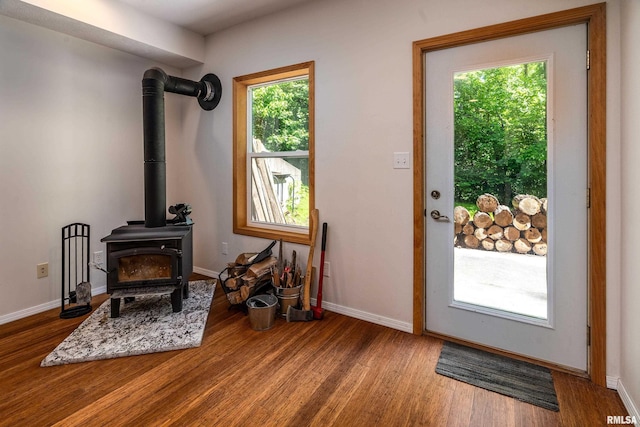entryway with wood finished floors, baseboards, and a wood stove