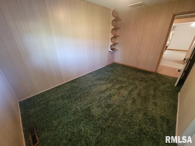 carpeted empty room with wood walls