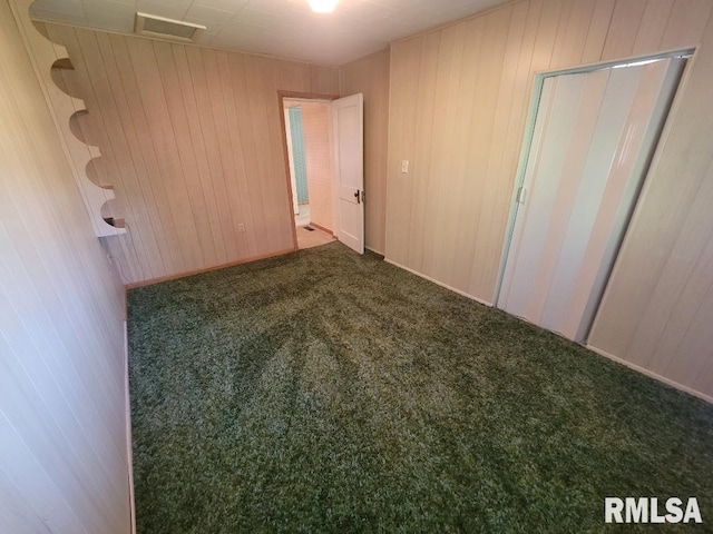 unfurnished bedroom featuring carpet flooring and wooden walls