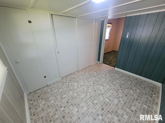 unfurnished bedroom featuring wood walls and a closet