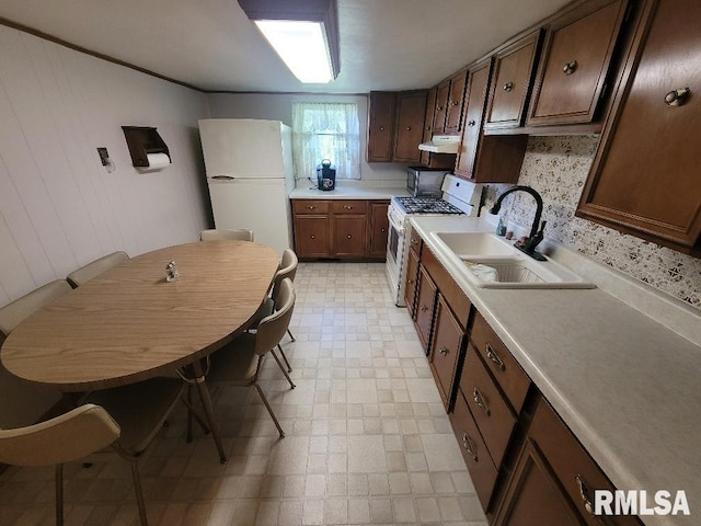 kitchen featuring white appliances, a sink, range hood, light flooring, and light countertops