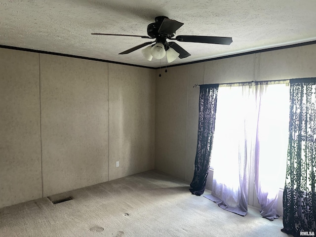 empty room featuring a ceiling fan, carpet floors, and a textured ceiling