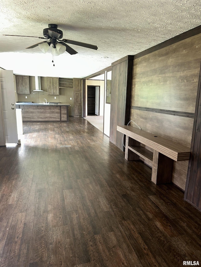 unfurnished living room featuring a ceiling fan, wood finished floors, and a textured ceiling