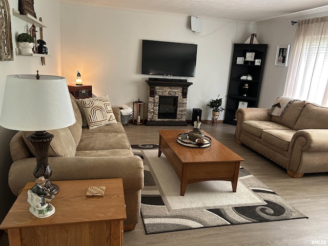 living area featuring wood finished floors, a fireplace, and a textured ceiling