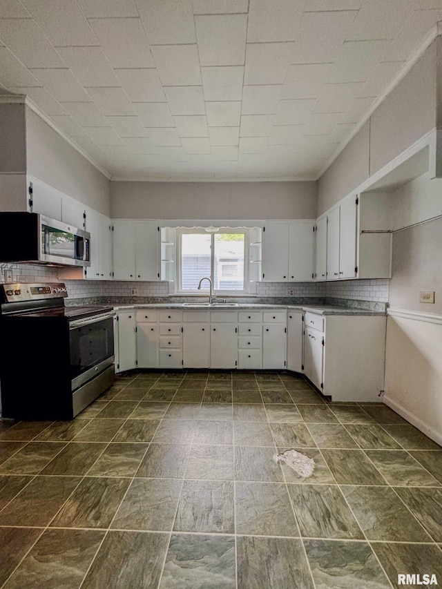 kitchen featuring appliances with stainless steel finishes, white cabinetry, backsplash, and a sink