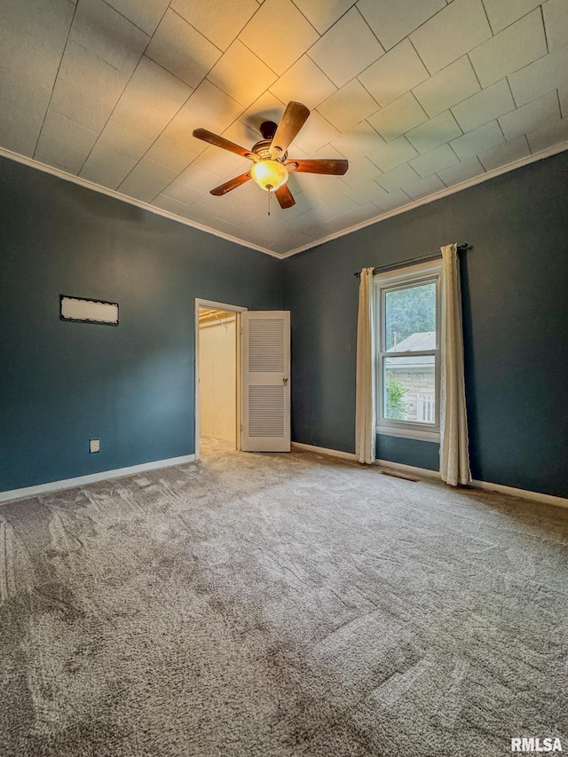 unfurnished bedroom with ornamental molding, carpet floors, baseboards, and ceiling fan