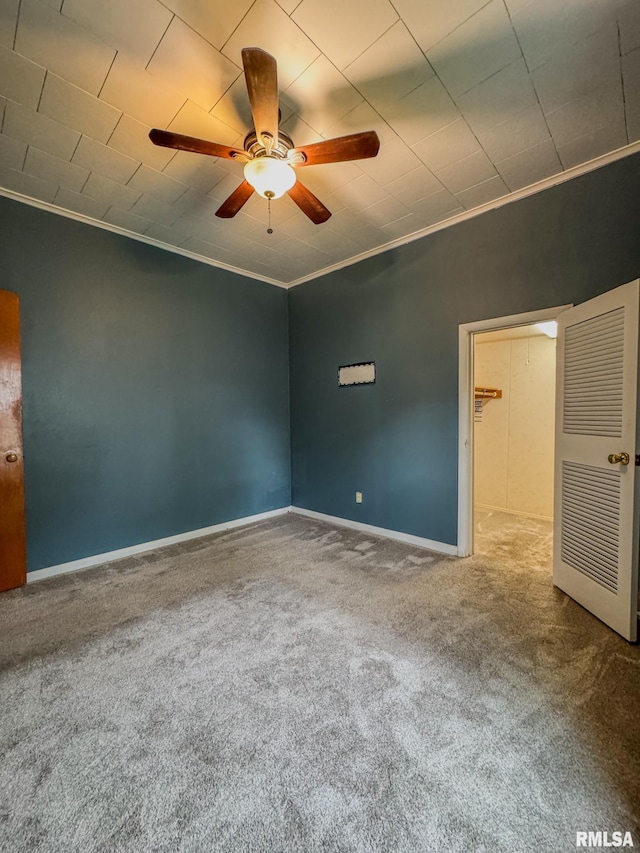spare room with ornamental molding, carpet flooring, ceiling fan, and baseboards