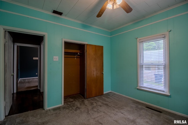 unfurnished bedroom with ornamental molding, carpet, a closet, a ceiling fan, and baseboards
