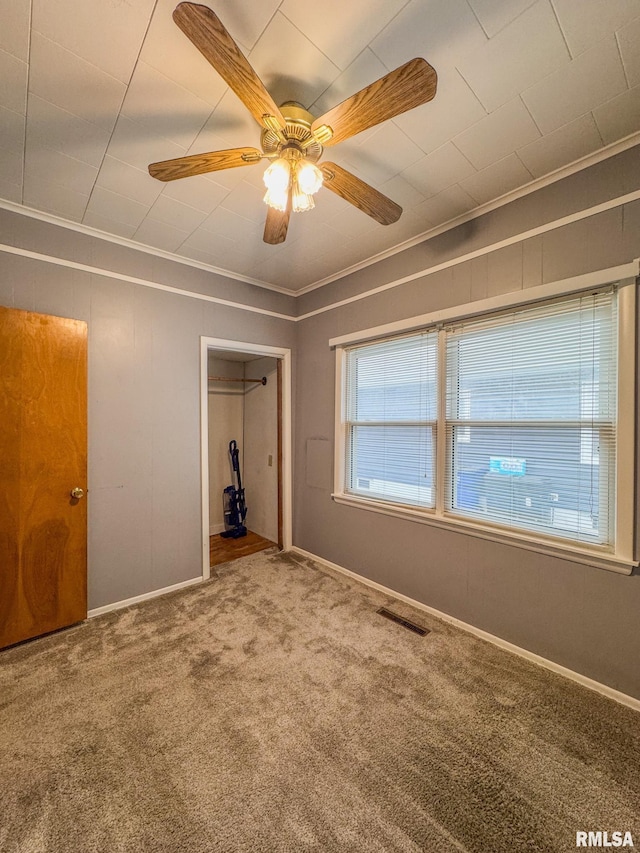 unfurnished bedroom with crown molding, carpet flooring, baseboards, and ceiling fan