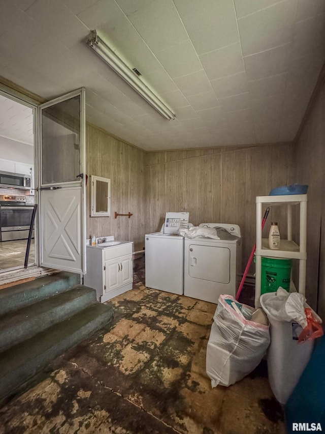laundry area featuring washing machine and clothes dryer and wood walls