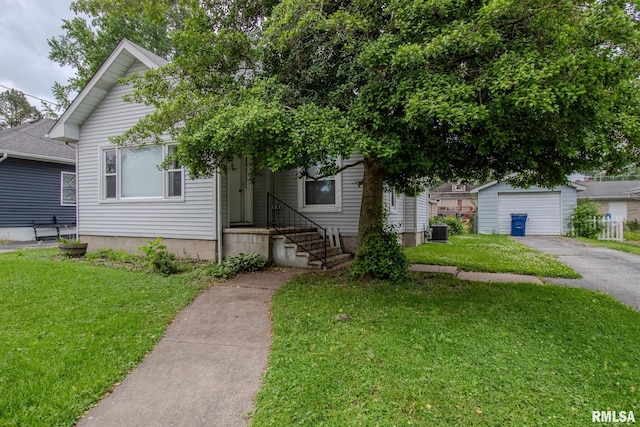 view of front of property with a front yard, central AC unit, asphalt driveway, and an outbuilding