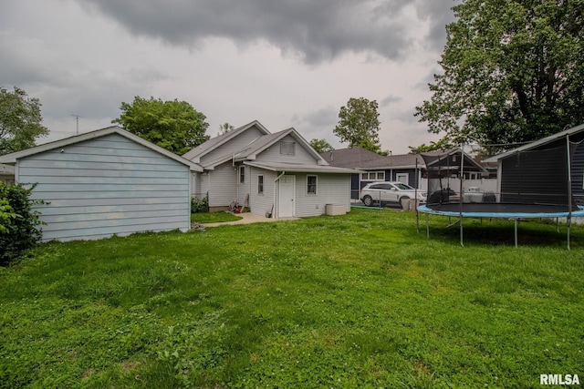 rear view of house with a trampoline and a yard