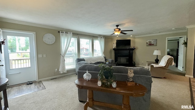 living area with light carpet, a glass covered fireplace, ceiling fan, ornamental molding, and baseboards