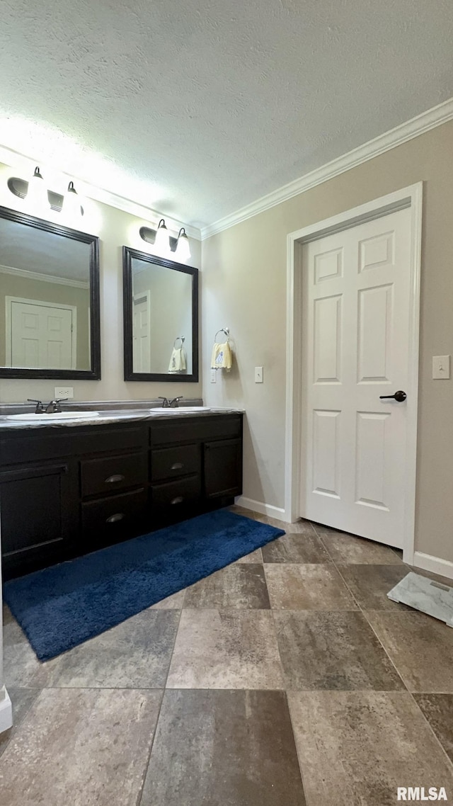 bathroom with ornamental molding, double vanity, baseboards, stone finish flooring, and a textured ceiling