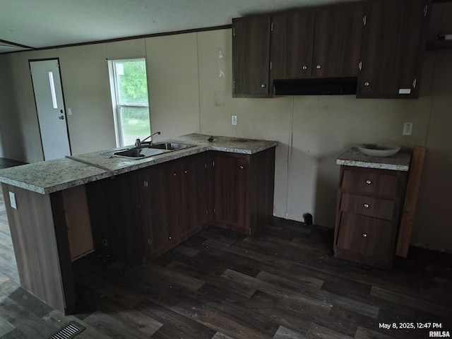 2709 Queens Ave, Odin, IL 62870 - kitchen with a sink, under cabinet range hood, a peninsula, dark wood-style flooring, and light countertops