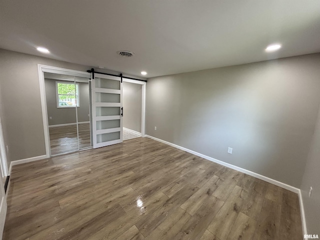 116 Lindsey Ave, Metropolis, IL 62960 - unfurnished bedroom with a barn door, baseboards, wood finished floors, recessed lighting, and a closet