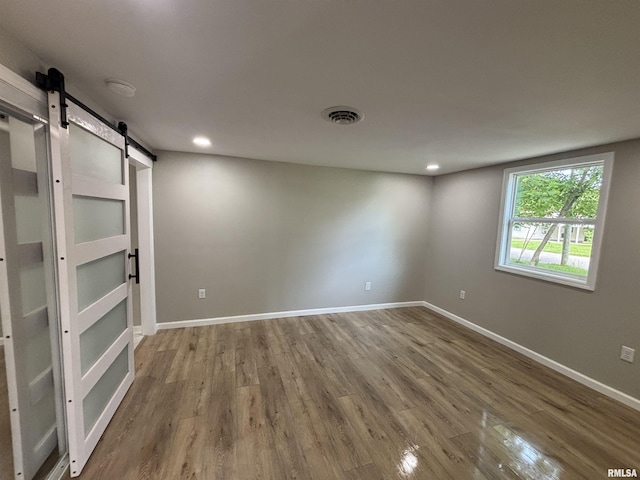 116 Lindsey Ave, Metropolis, IL 62960 - empty room featuring a barn door, wood finished floors, baseboards, and recessed lighting