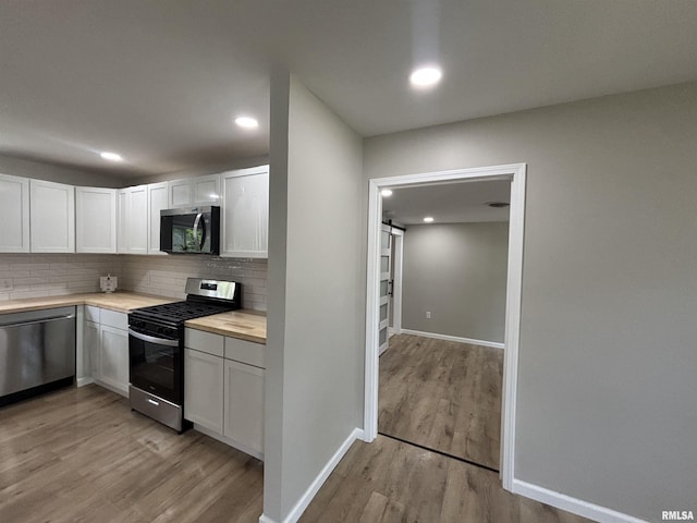 116 Lindsey Ave, Metropolis, IL 62960 - kitchen with appliances with stainless steel finishes, light countertops, decorative backsplash, light wood-style flooring, and white cabinets
