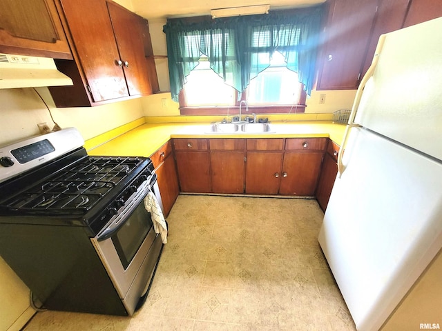 422 E Dr, Flora, IL 62839 - kitchen with freestanding refrigerator, stainless steel range with gas stovetop, a sink, under cabinet range hood, and light countertops