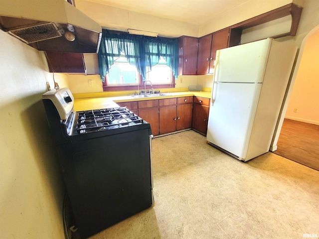 422 E Dr, Flora, IL 62839 - kitchen featuring gas stove, under cabinet range hood, freestanding refrigerator, a sink, and light countertops
