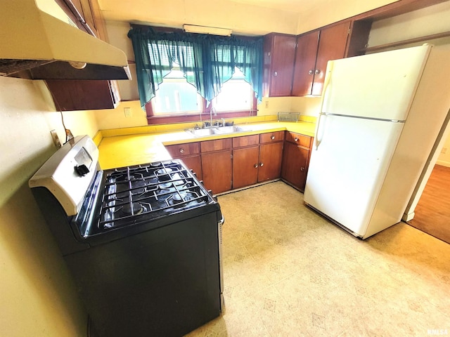 422 E Dr, Flora, IL 62839 - kitchen featuring range with gas cooktop, freestanding refrigerator, under cabinet range hood, a sink, and light floors