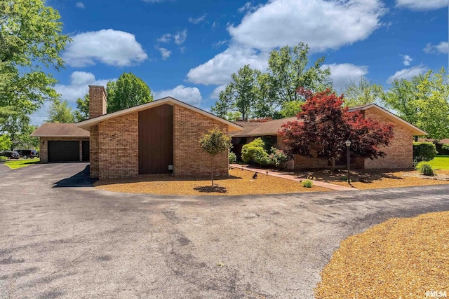 415 E Reichert Dr, Marion, IL 62959 - view of front of house featuring a chimney, asphalt driveway, an attached garage, and brick siding