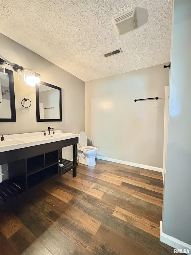 910 Fairlane Dr, Marion, IL 62959 - bathroom featuring toilet, wood finished floors, double vanity, a textured ceiling, and baseboards