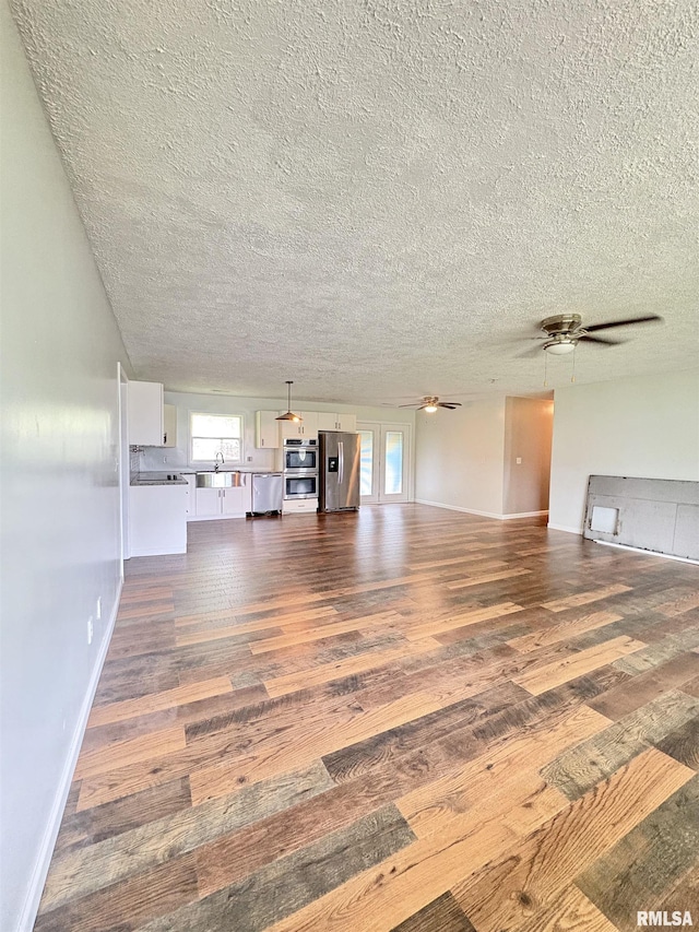 910 Fairlane Dr, Marion, IL 62959 - unfurnished living room featuring dark wood-style flooring, a textured ceiling, plenty of natural light, a ceiling fan, and baseboards
