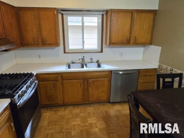 415 Marteeny St, Mount Vernon, IL 62864 - kitchen featuring appliances with stainless steel finishes, a sink, under cabinet range hood, brown cabinetry, and light countertops