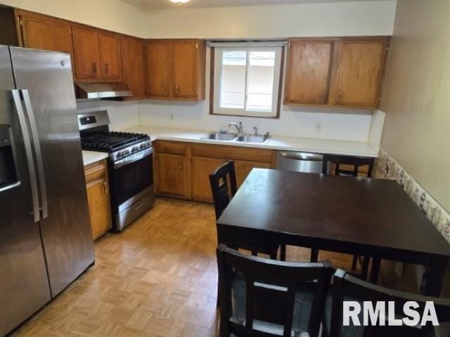 415 Marteeny St, Mount Vernon, IL 62864 - kitchen with stainless steel appliances, a sink, under cabinet range hood, brown cabinetry, and light countertops