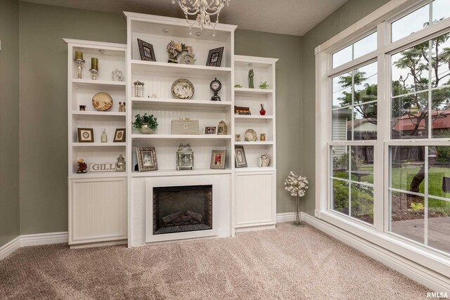213 Texas Ave, Carterville, IL 62918 - unfurnished living room featuring light colored carpet, baseboards, a chandelier, and a large fireplace