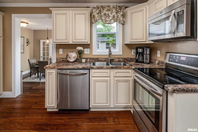 213 Texas Ave, Carterville, IL 62918 - kitchen with stainless steel appliances, a sink, cream cabinetry, dark countertops, and ornamental molding